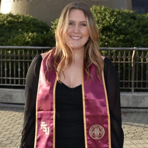 Leila in front of a sculpture in a graduation gown