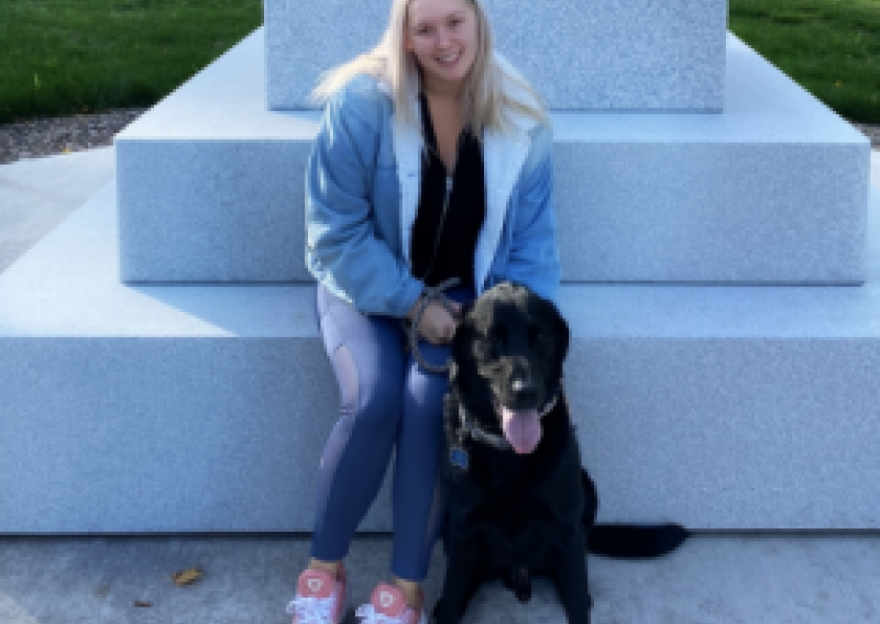 NHC PGH member Laurel smiling in front of a statue with her dog