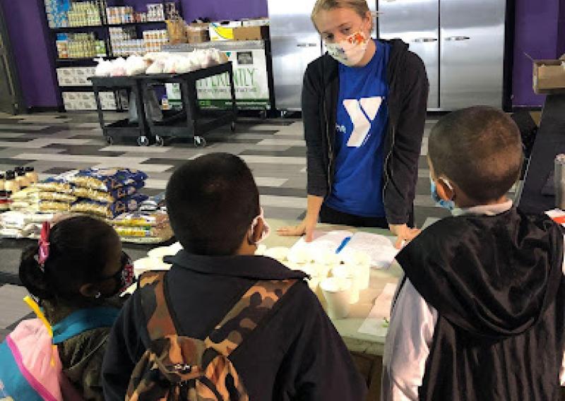 Discussing healthy food and growing your own food with youth at a tasting event for Kale Chips during the food pantry. 