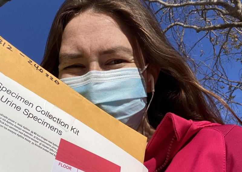 Catherine is seen here taking a selfie during service. She is holding a box marked with a label that says urine samples. 