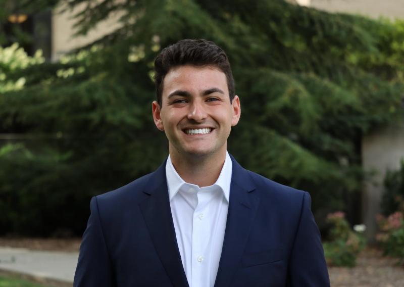 NHC member Brendan Reitman wearing a suit and smiling.