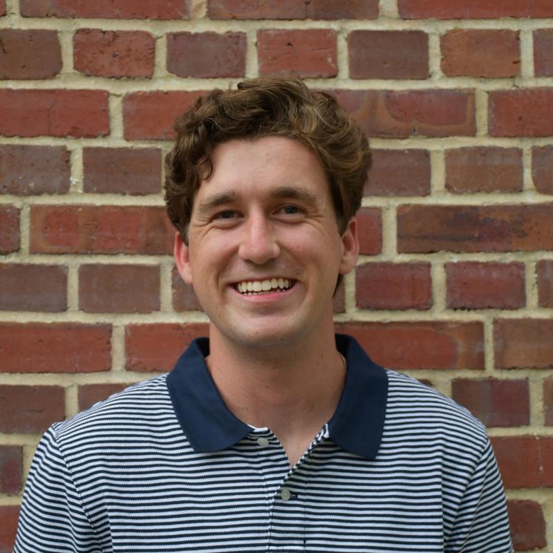 NHC member Jack Sommerville wearing a blue and white striped shirt and smiling.