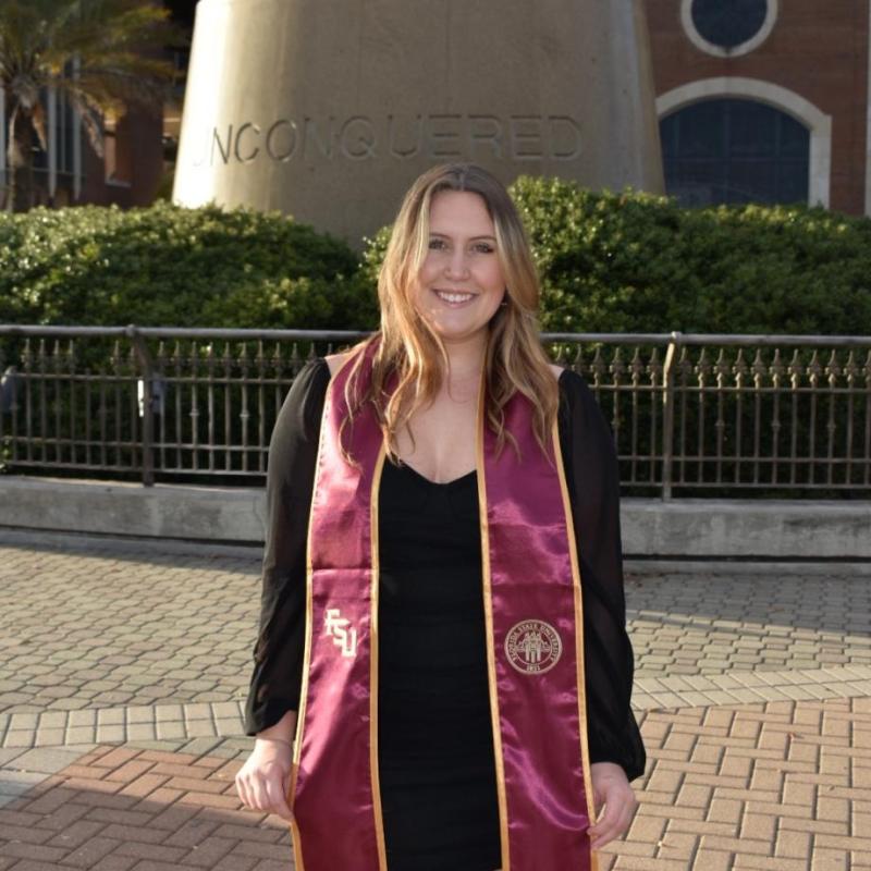 Leila in front of a sculpture in a graduation gown