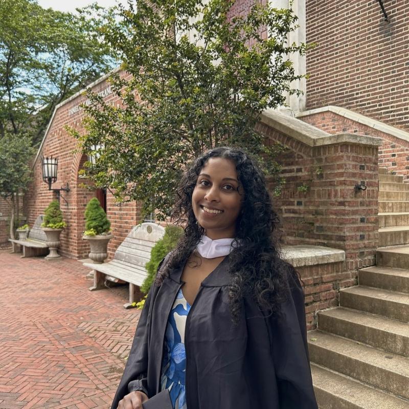 Maya standing in a courtyard in a graduation gown
