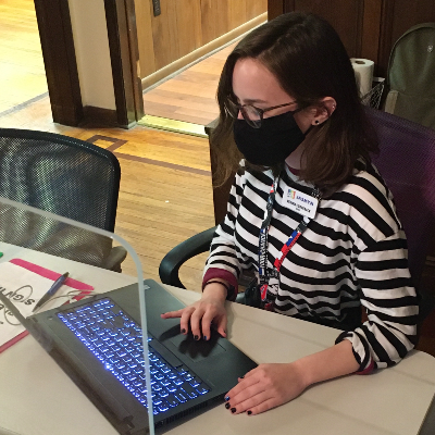 Regina at her desk using a laptop to coordinate resources and services to clients