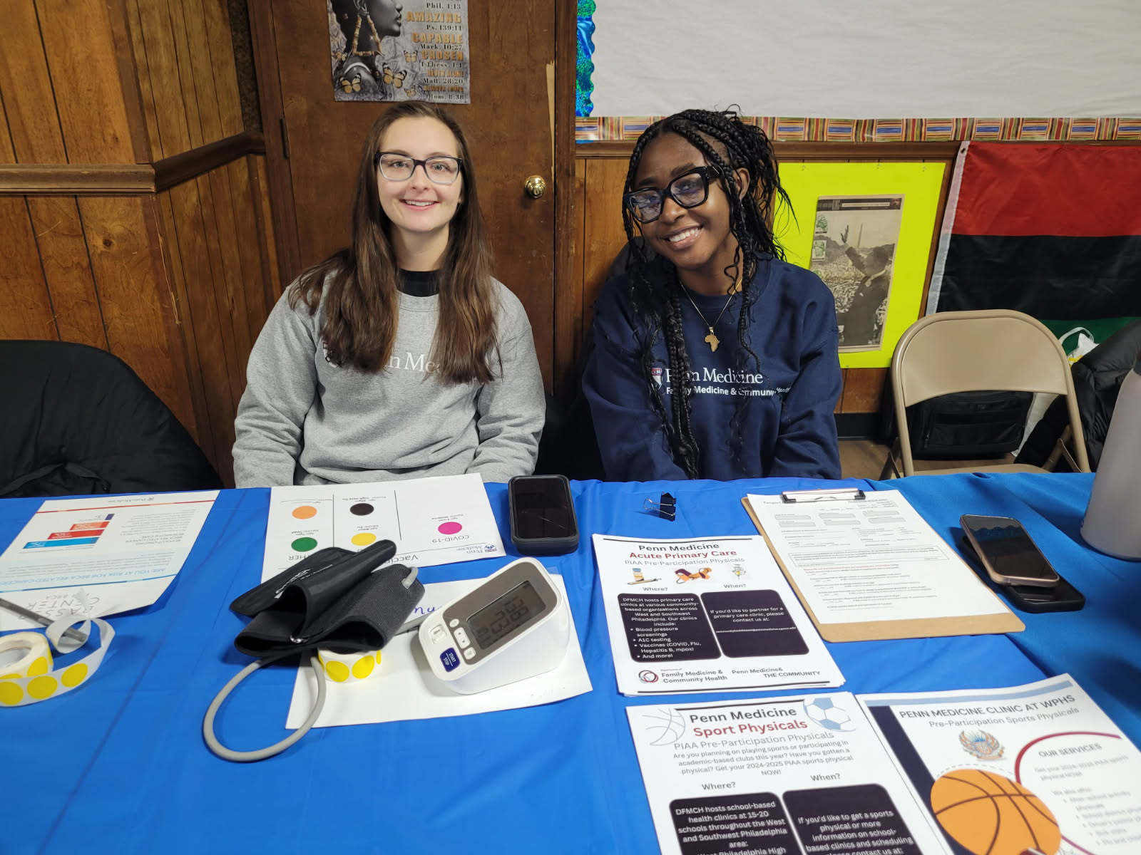 "NHC Philly Members Chanita and Catherine, wearing blue and grey Penn Medicine sweaters, while serving at the Miller Memorial Baptist Church Health and Wellness Fair"