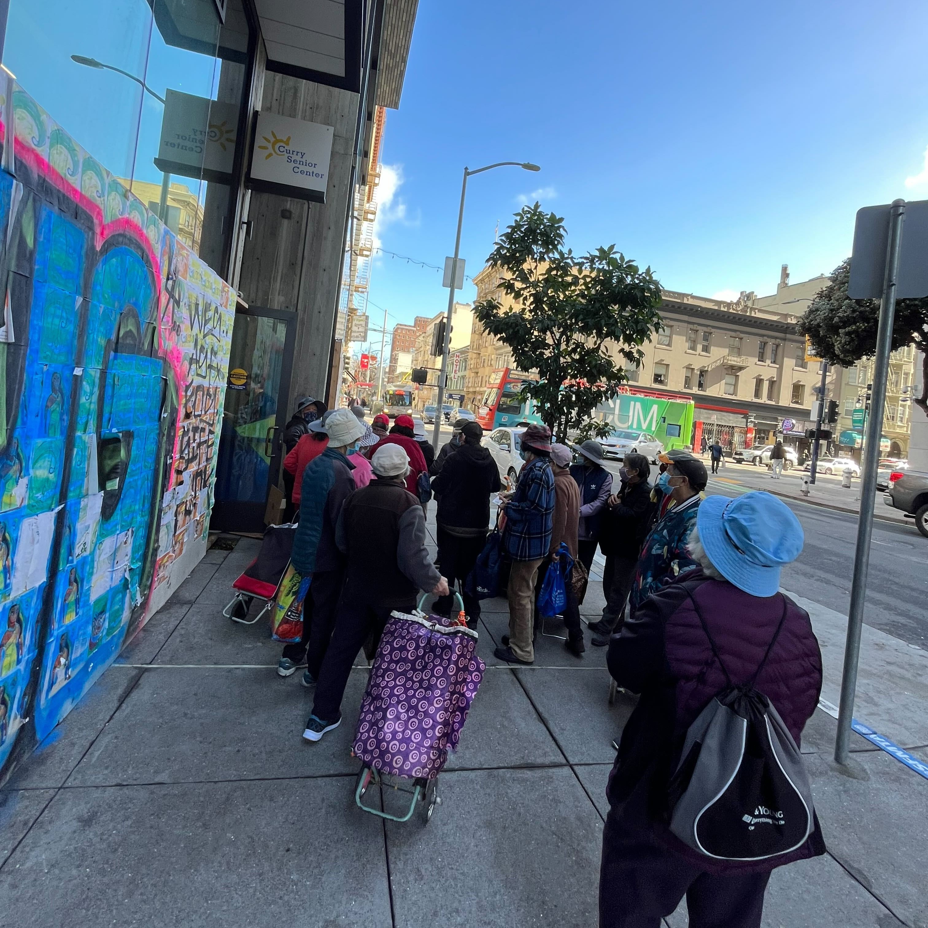 A group of older adults meeting outside of Curry Senior Center, on their way to a field trip. 