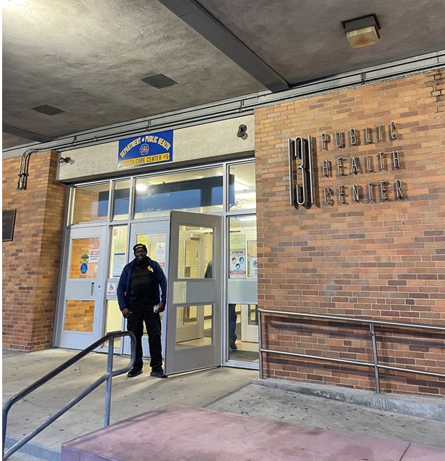 A security guard standing in front of a brick building that says public health center